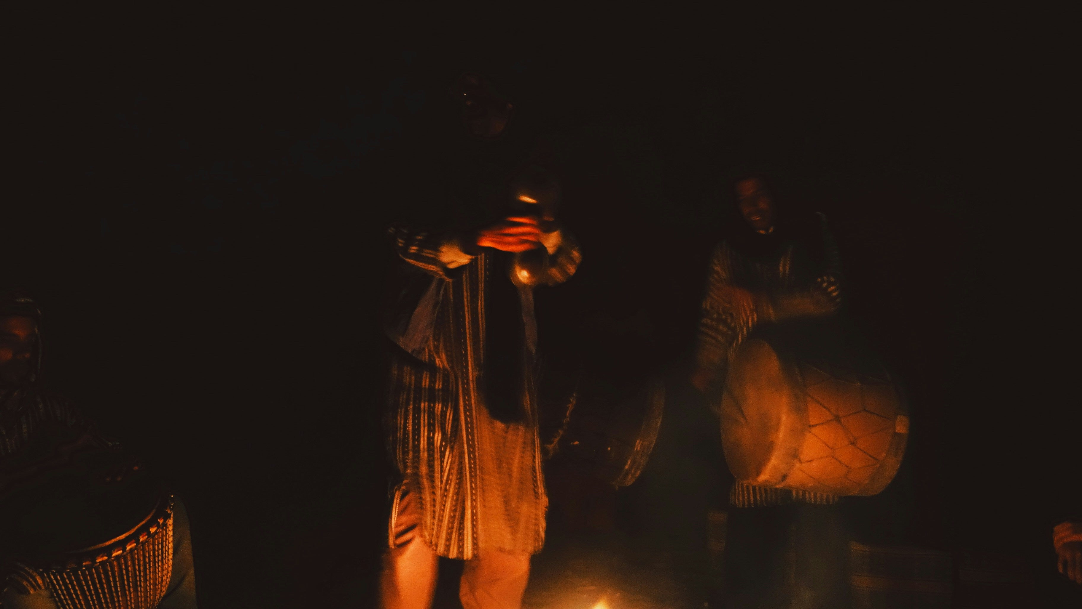 Dancers performing in a dark setting with warm lighting