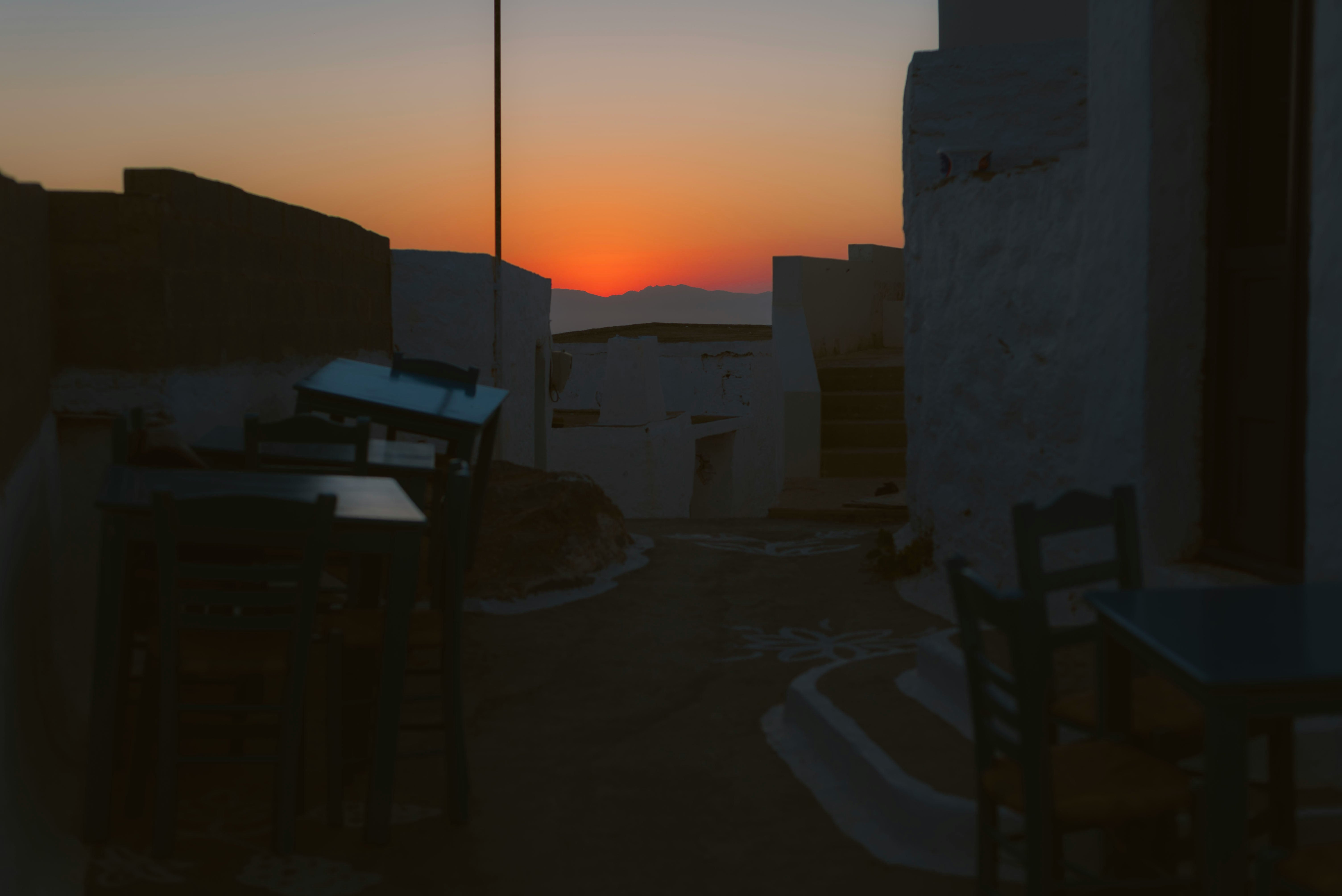 Sunset over a coastal town with white buildings and a clear sky.