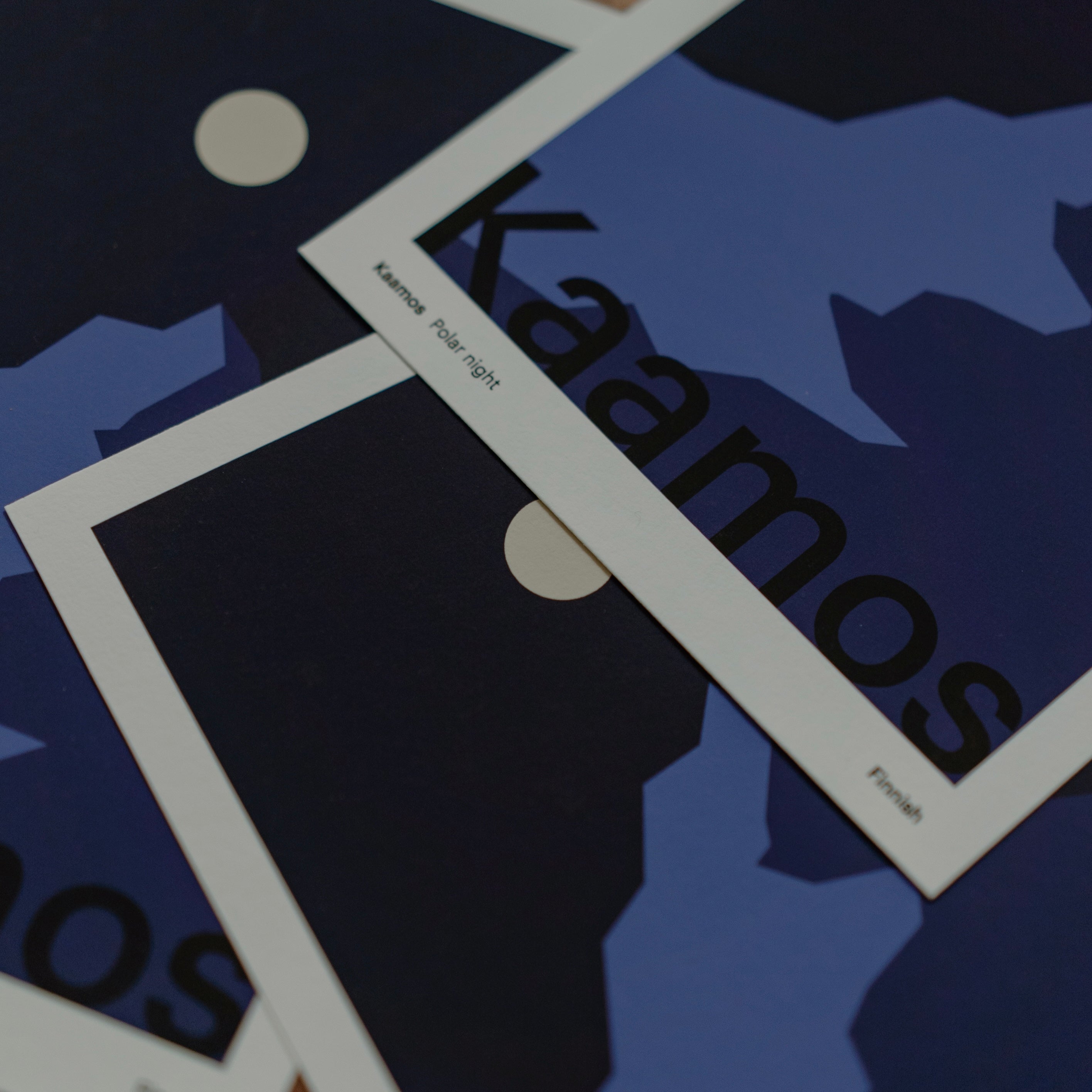 Blue, dark blue and white prints with 'Kaamos' text