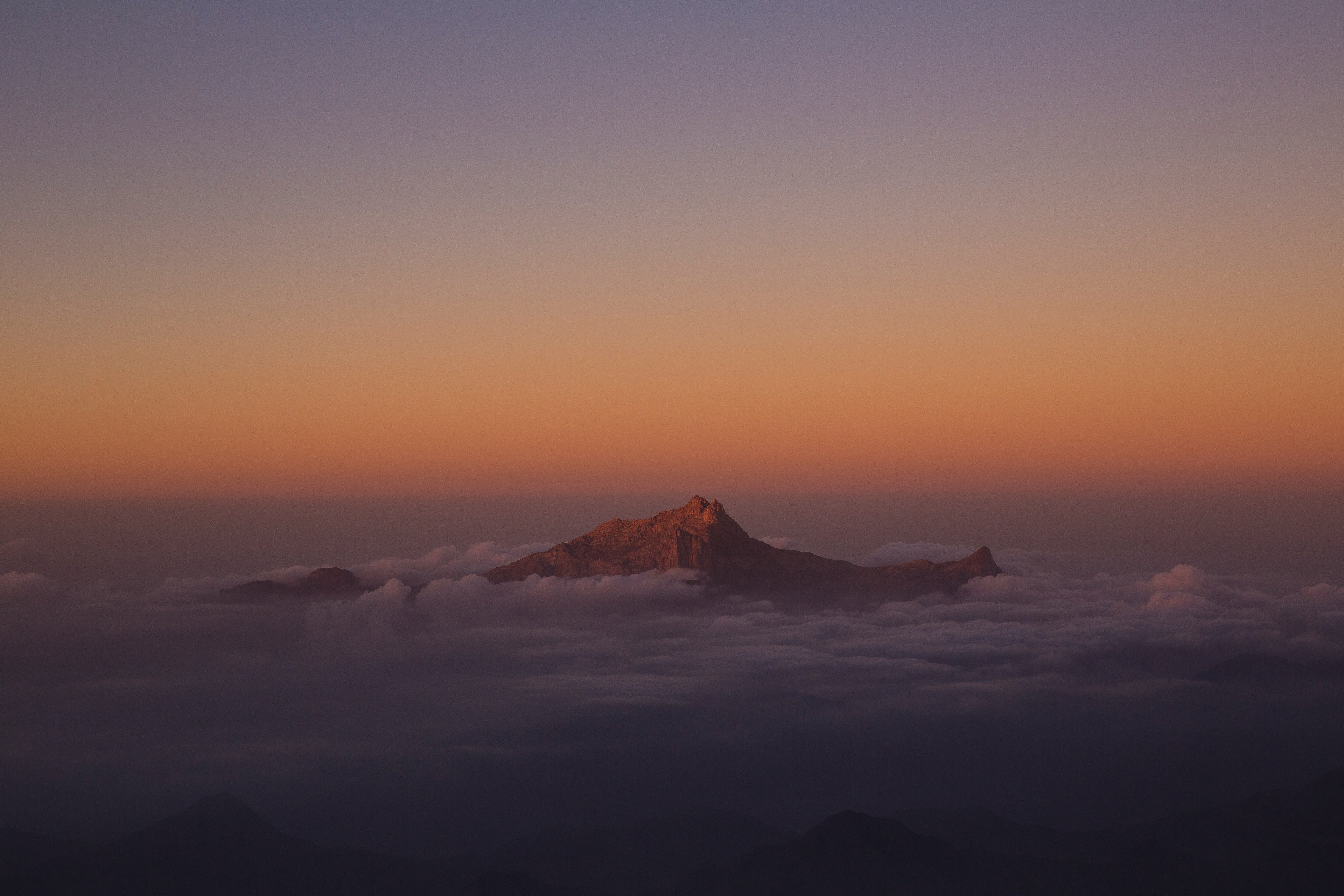 Mountain poking through clouds at sunset